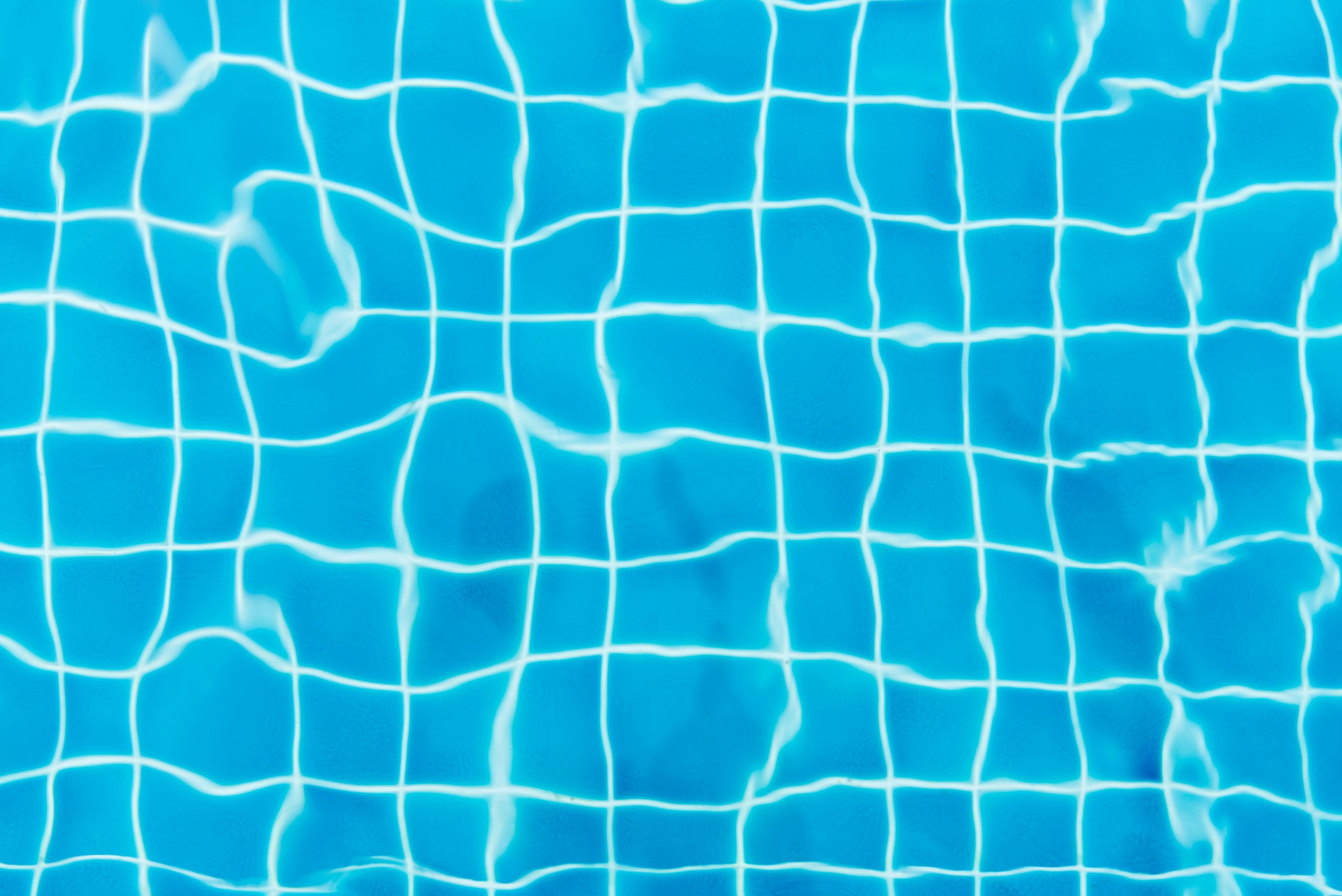 close-up of clear blue pool water, with the tiled floor visible underneath